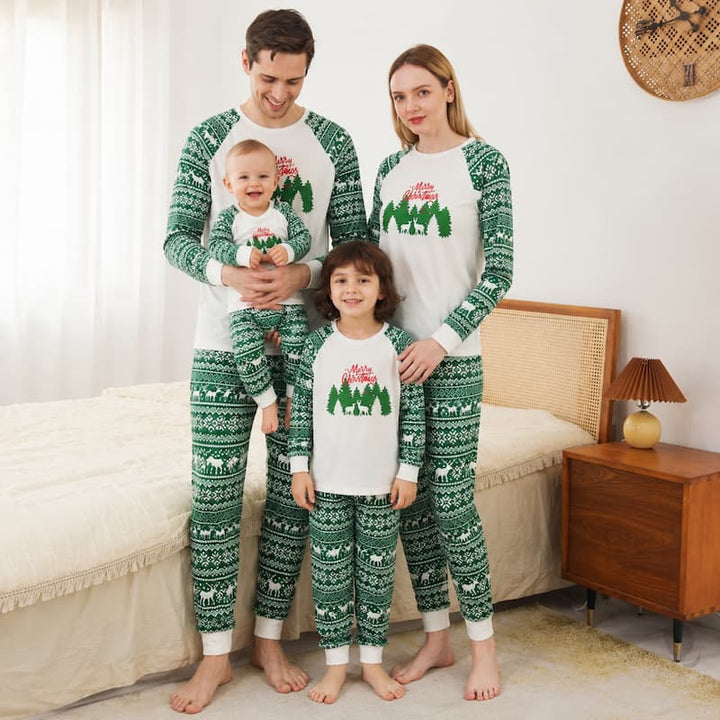 A family of four wearing matching Christmas-themed long-sleeve pajamas stands together in a bedroom. The pajamas are white with green Nordic-style patterns and a tree graphic with the word 'Merry'.
